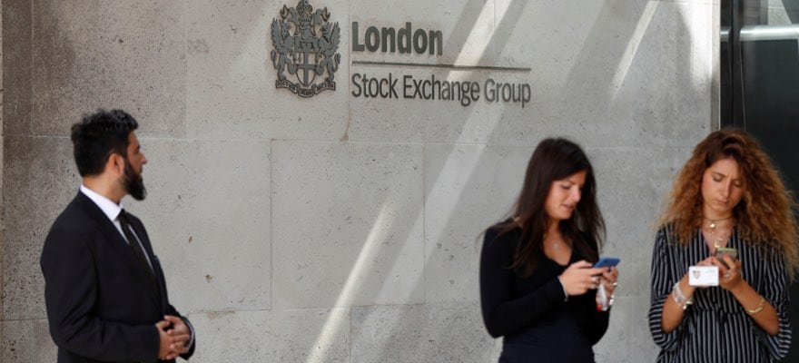 People check their mobile phones as they stand outside the entrance of the London Stock Exchange in London